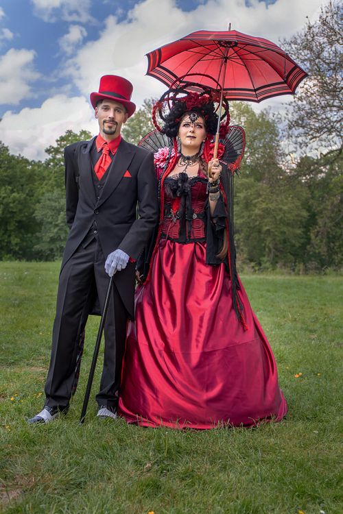 Free Elegantly dressed steampunk couple posing outdoors with umbrellas, showcasing fashion style. Stock Photo