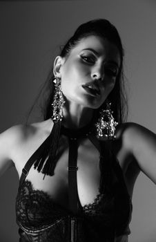Artistic black and white portrait of a woman in a studio, showcasing fashion jewelry and lingerie.