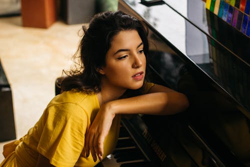 Woman Wearing Yellow Shirt Leaning On Grand Piano