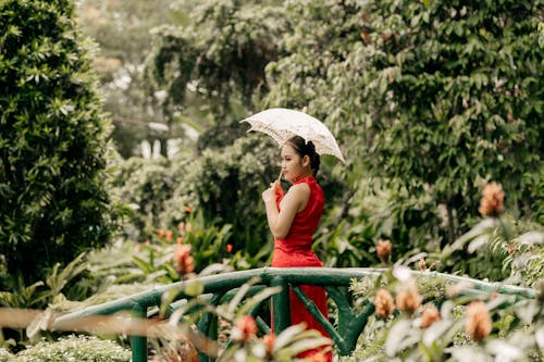 Young Woman in a Red Dress Standing in the Garden