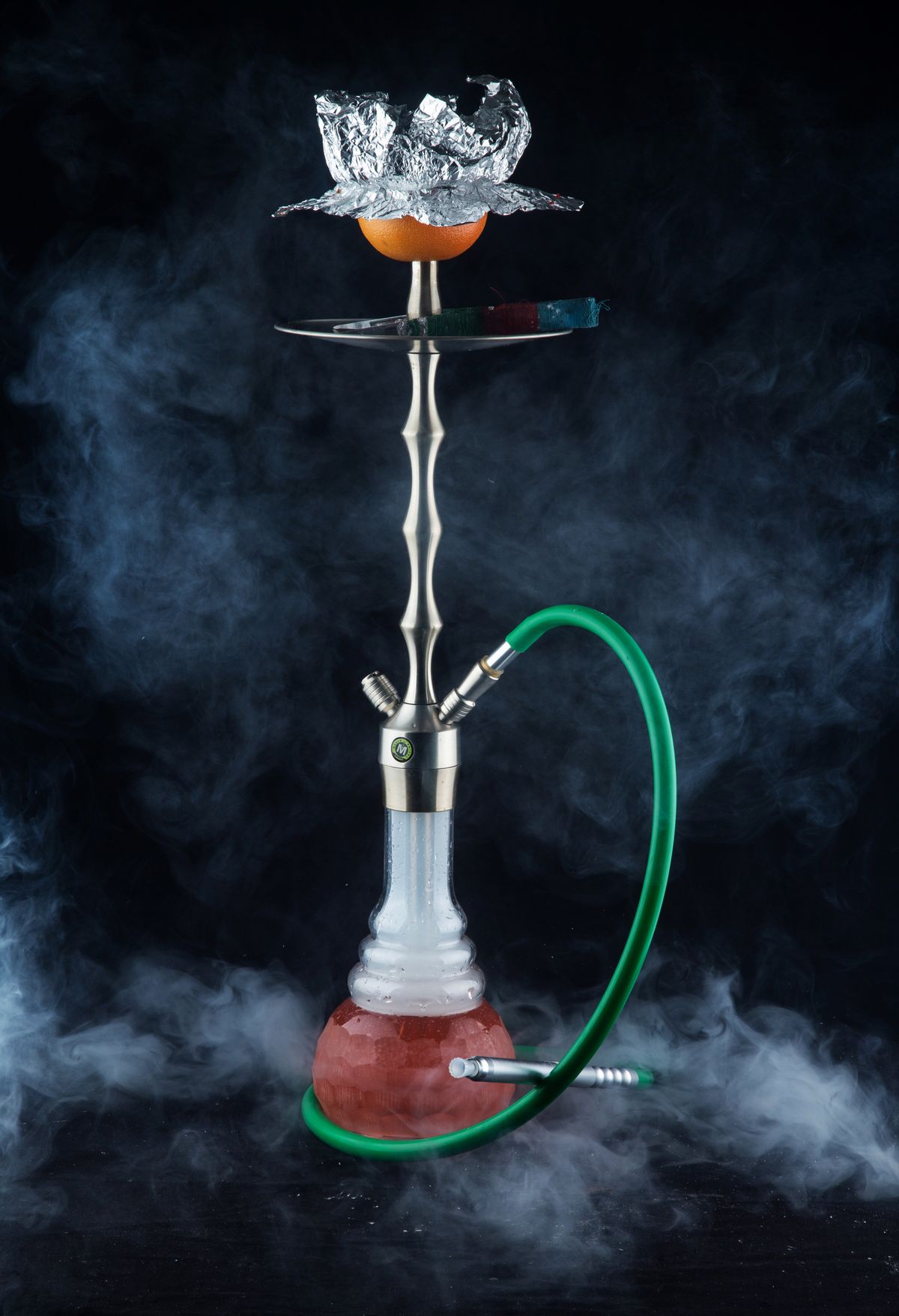 A hookah surrounded by smoke against a dark backdrop