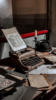 A nostalgic desk setup featuring an old typewriter, papers, and candlestick.
