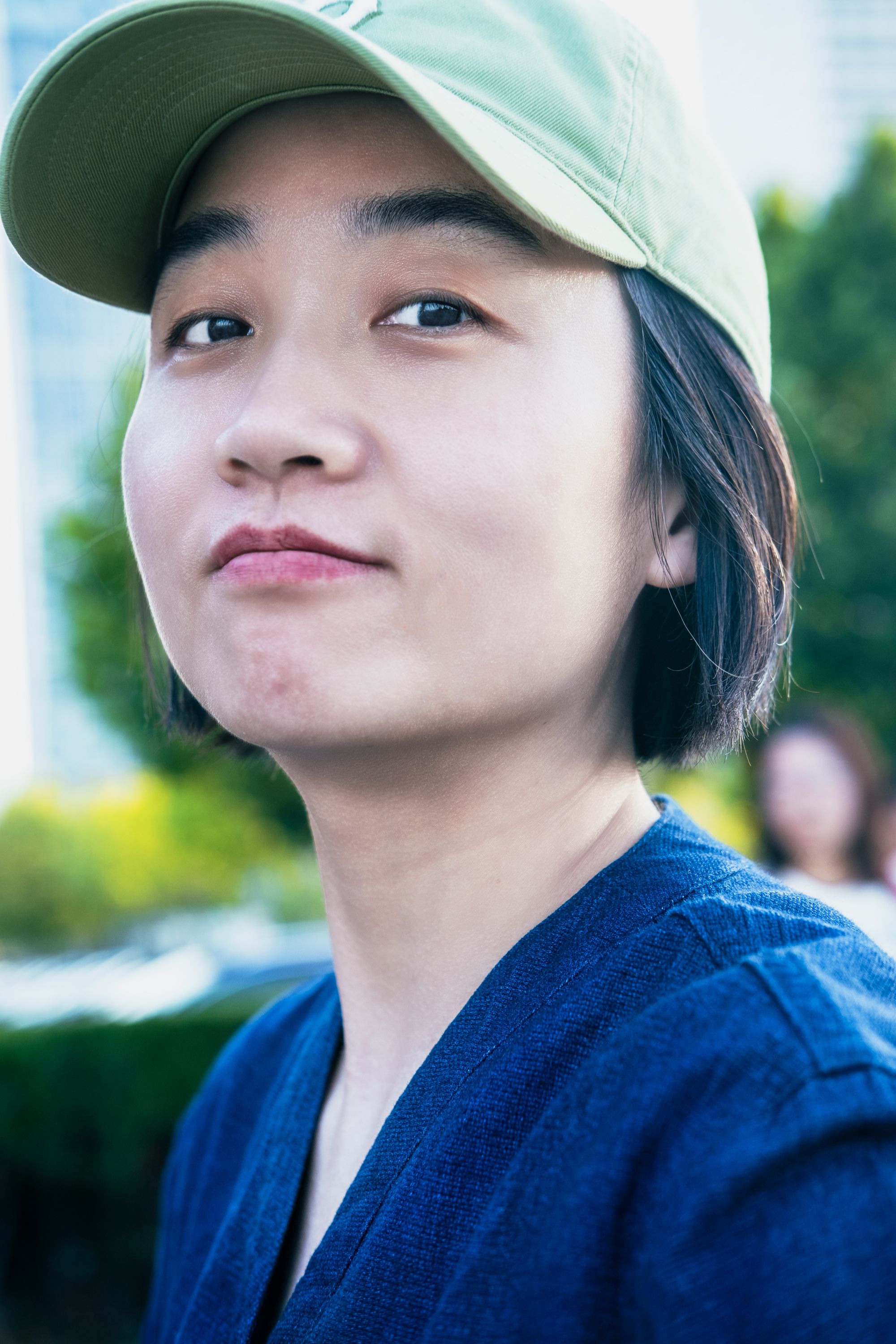 Close-up portrait of a young woman in a cap enjoying a summer day outdoors.