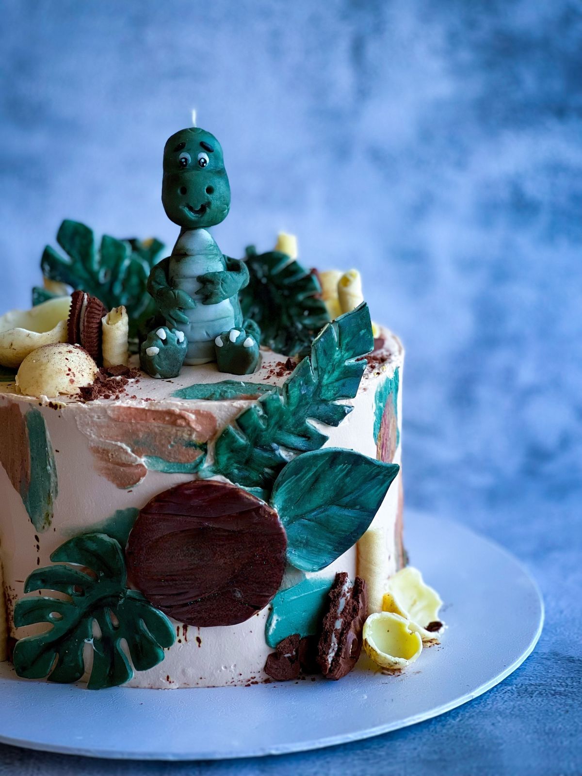 Colorful dinosaur-themed cake with fondant decorations, perfect for birthdays. Stock Photo.