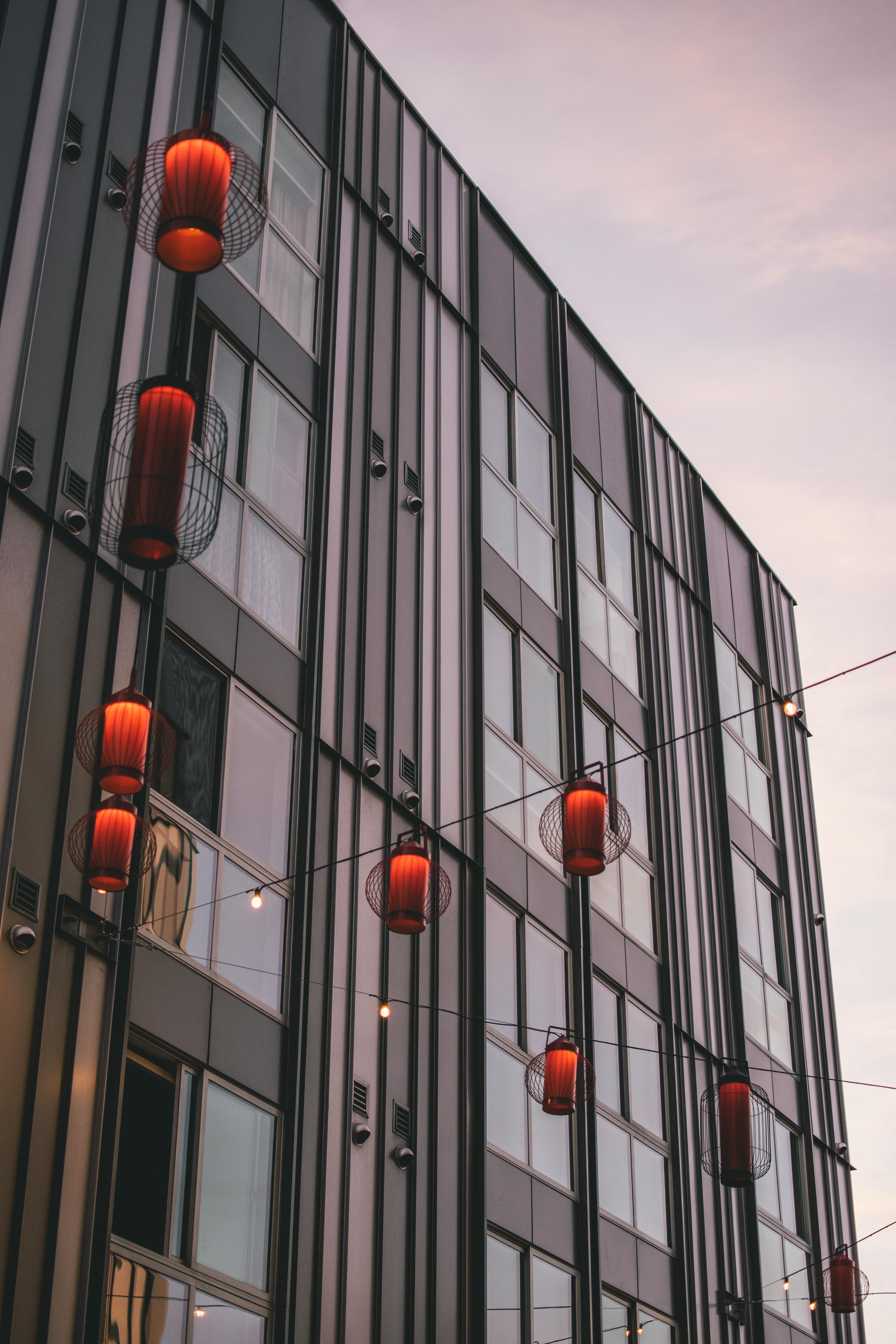 Contemporary building exterior with hanging red lanterns at dusk.