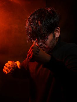Dramatic studio portrait of a male boxer posing in red lighting.