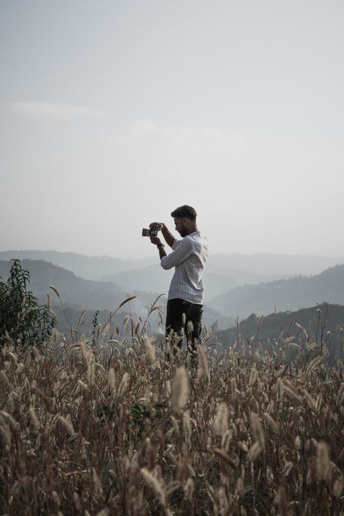 Free A photographer stands in a misty field capturing scenic hills in Srinagar. Stock Photo
