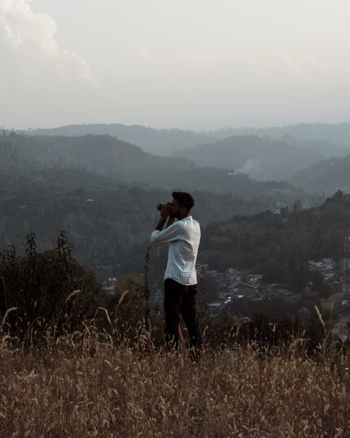 Free A man stands taking pictures on a hilltop, capturing scenic views in Srinagar. Stock Photo