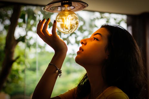 Woman Looking And Touching Bulb