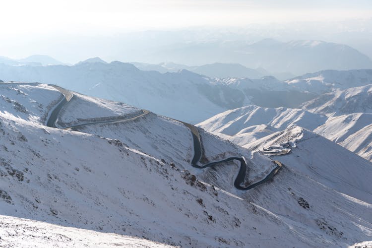 Panorama Of Snow Covered Mountains With A Serpentine Road