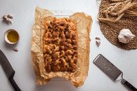 Top view of freshly baked focaccia on parchment paper with garlic and wheat decor.