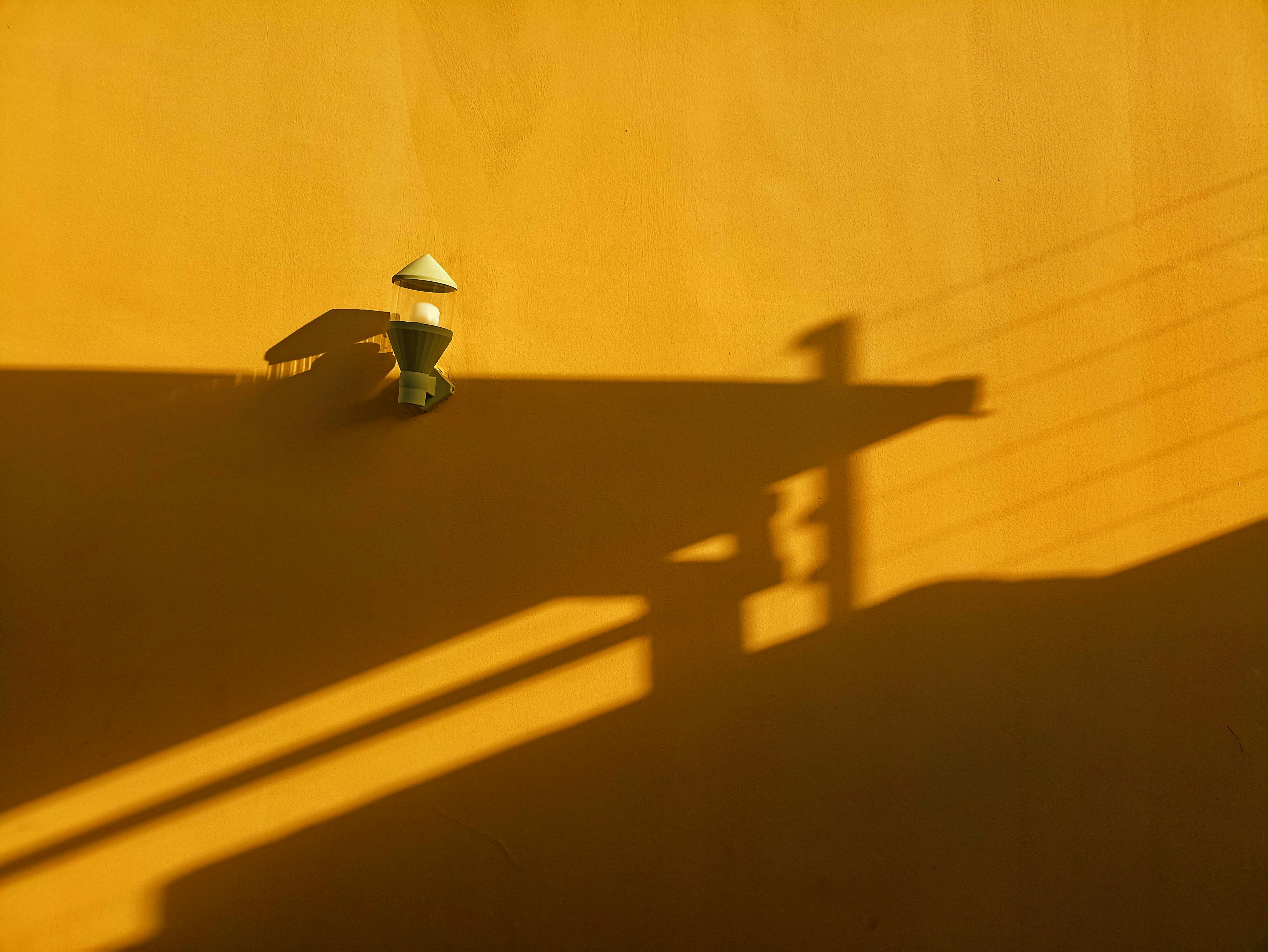 A minimalistic view of a yellow wall with light fixture casting shadows, captured in Jos, Nigeria.