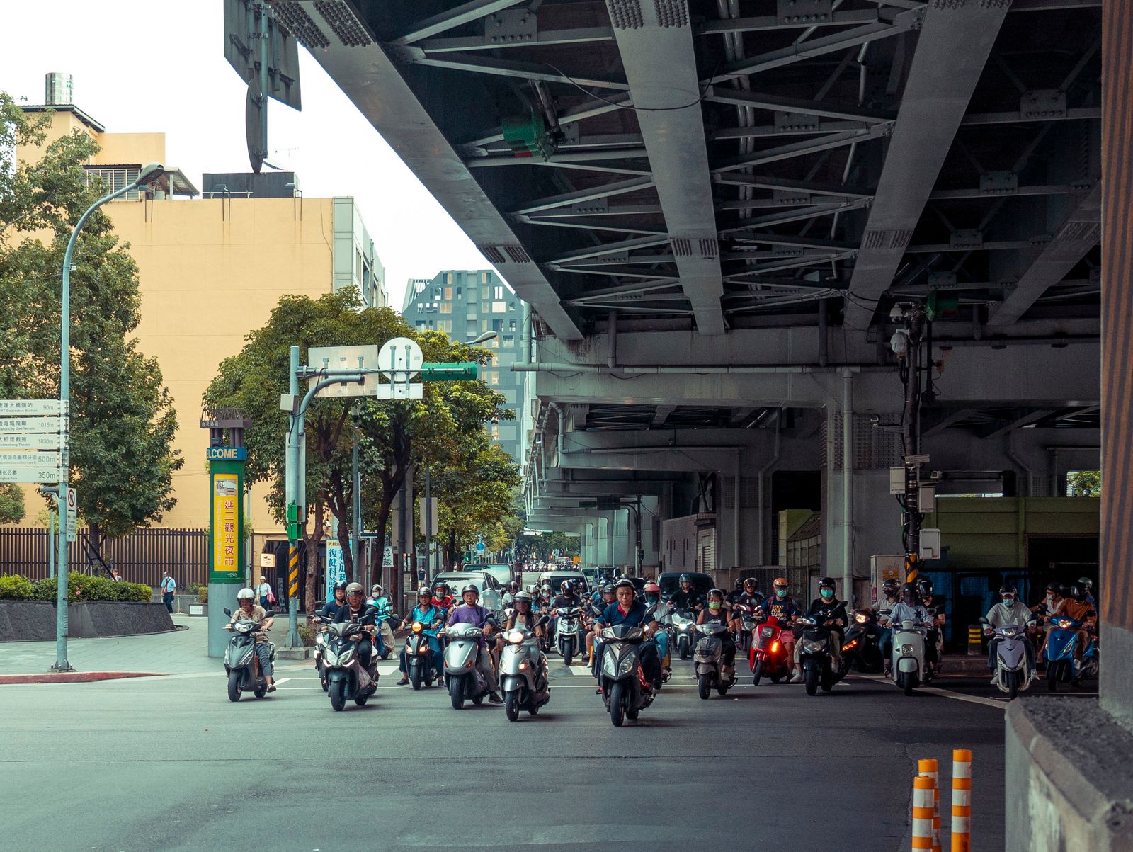 Rue urbaine animée avec de nombreux scooters sous un pont