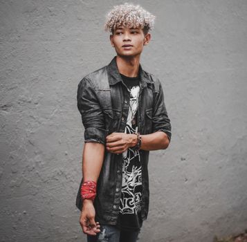 Fashionable young man posing against a concrete wall wearing modern streetwear.