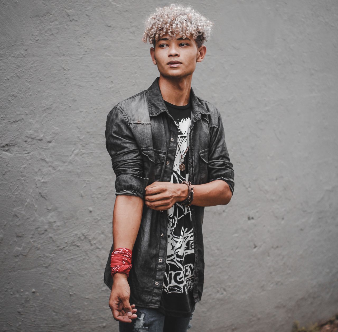 fashionable young man posing against a concrete wall wearing modern st