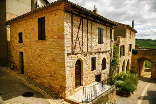 Free Rustic stone houses line a picturesque village street under a sunny sky. Stock Photo