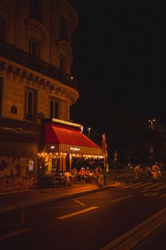 Cozy Paris café at night with people enjoying the vibrant atmosphere on a city street corner.