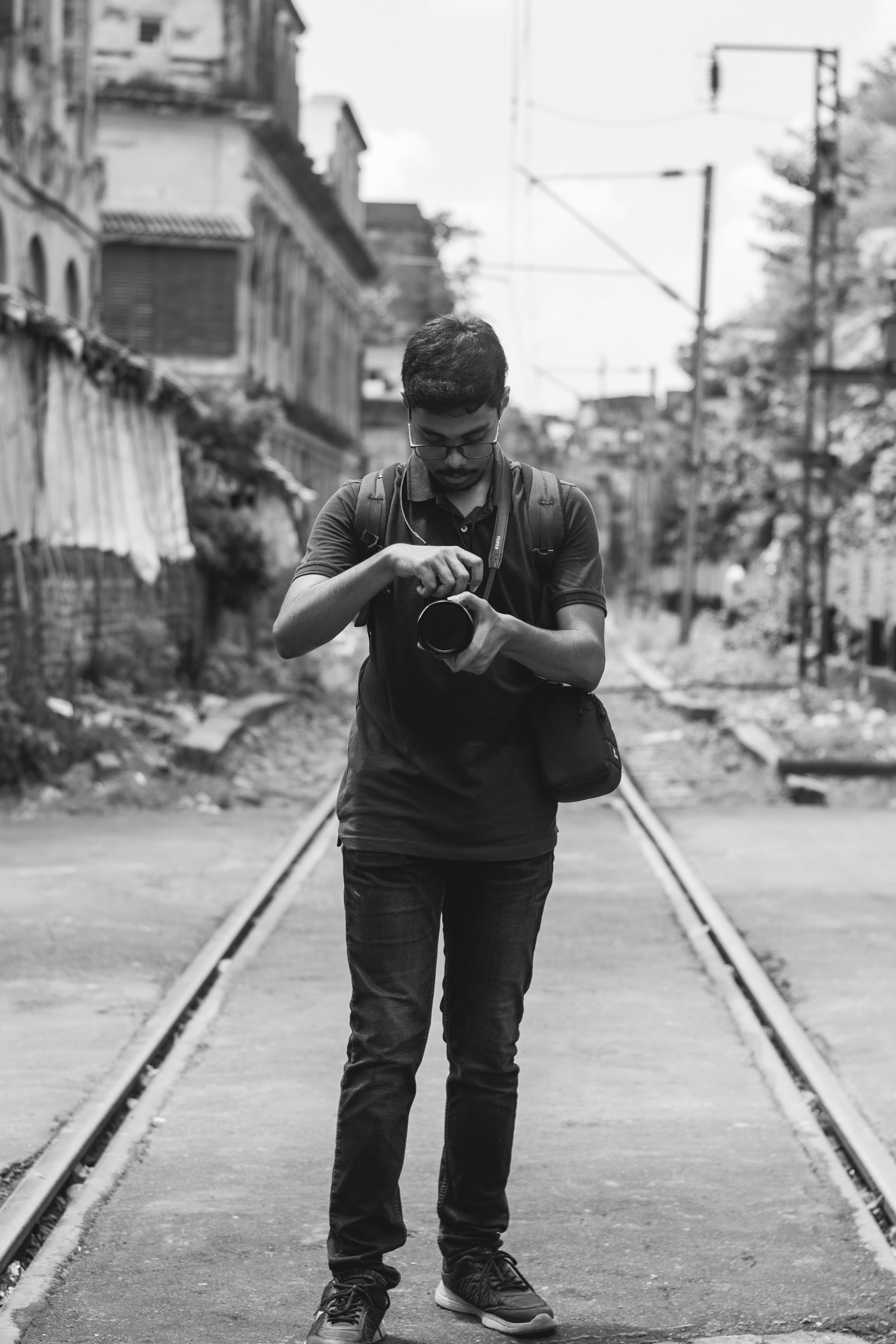 Black and white photo of a man with a camera on railway tracks in Kolkata, India.