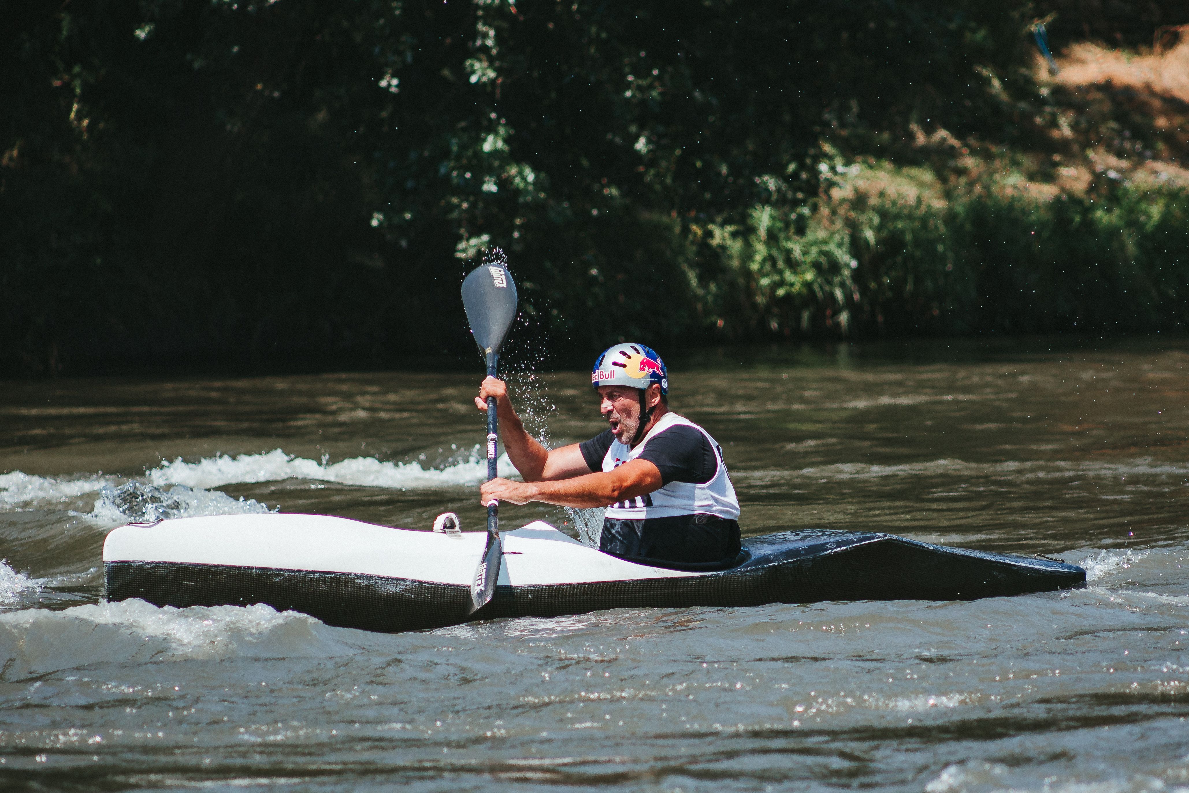 Focused man competing in a canoeing race on a turbulent river.