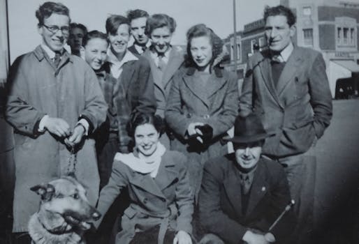A classic black and white photo featuring a group of friends with a dog in a street setting.