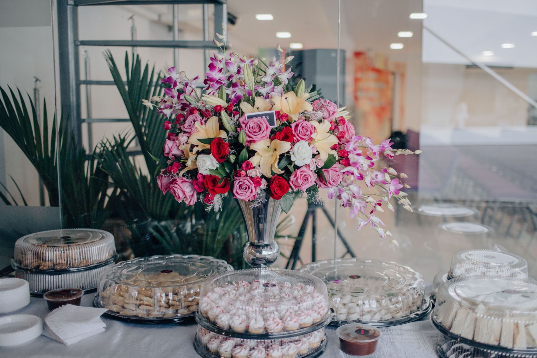A vibrant floral centerpiece with pink and red roses on a dining table set for an event indoors.