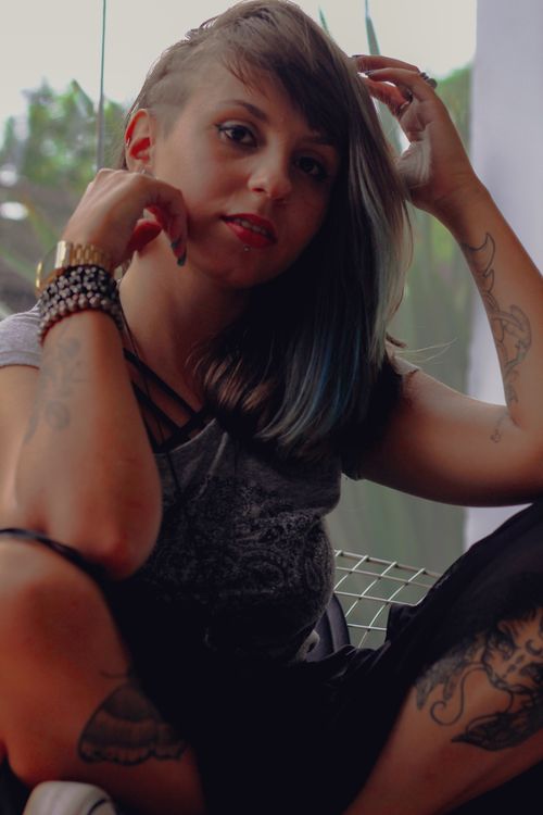 Free Portrait of a young tattooed woman with unique hairstyle relaxing indoors. Stock Photo