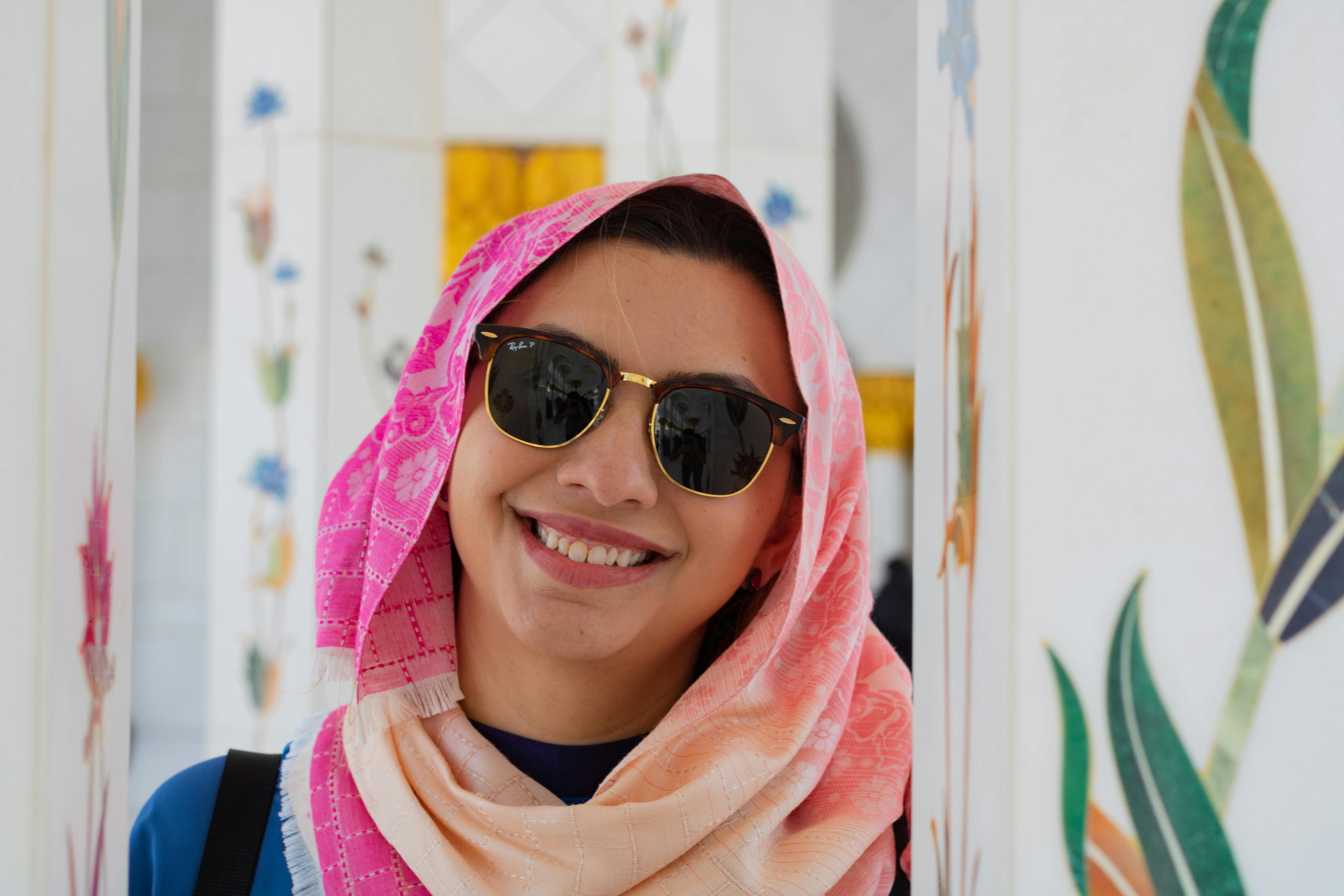 一位开朗的女人戴着太阳镜和充满活力的头巾，站在装饰着艺术品的室内
