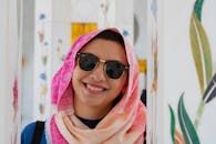 一位开朗的女人戴着太阳镜和充满活力的头巾，站在装饰着艺术品的室内