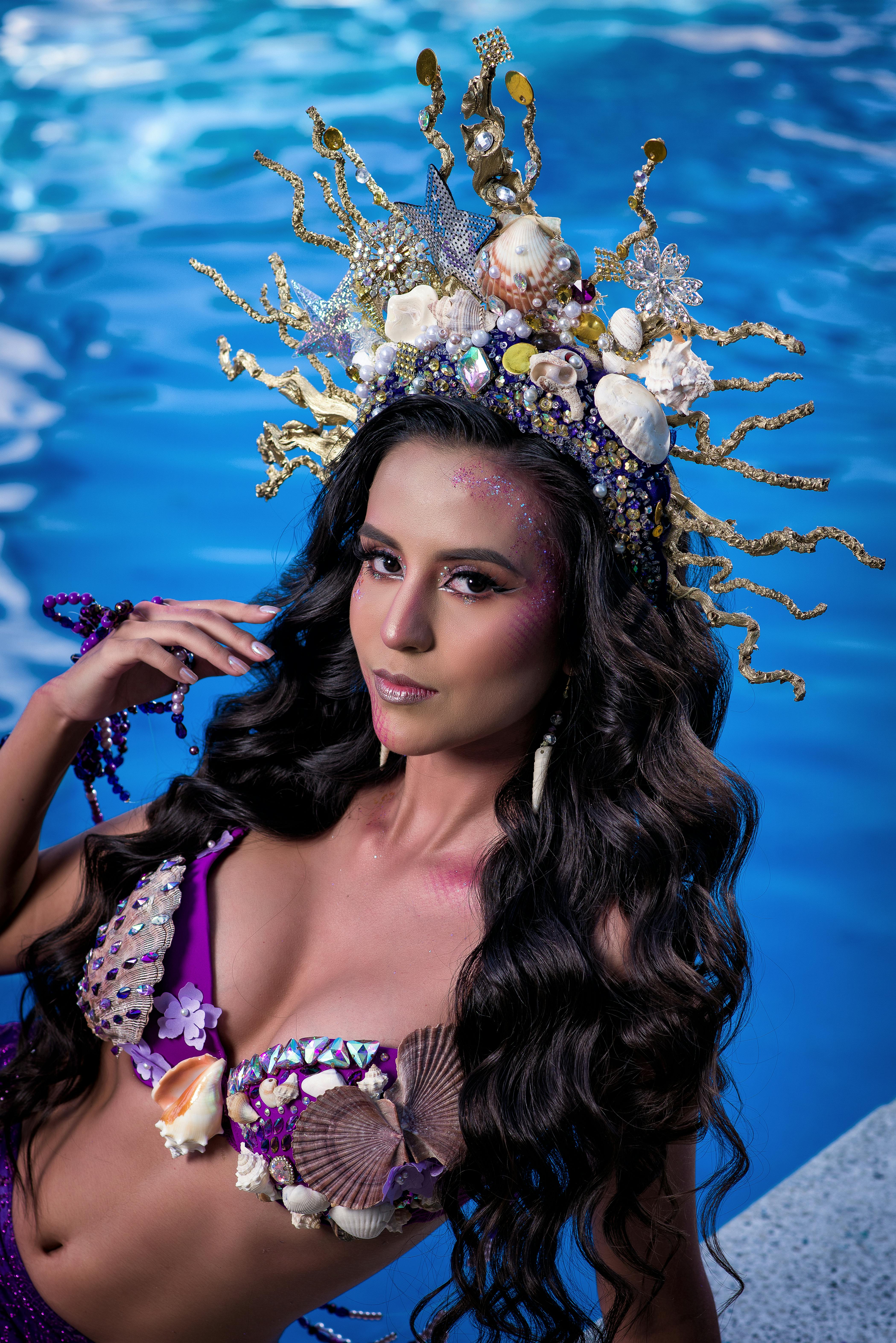 Elegant woman with seashell crown posing by the poolside, exuding fantasy fashion.
