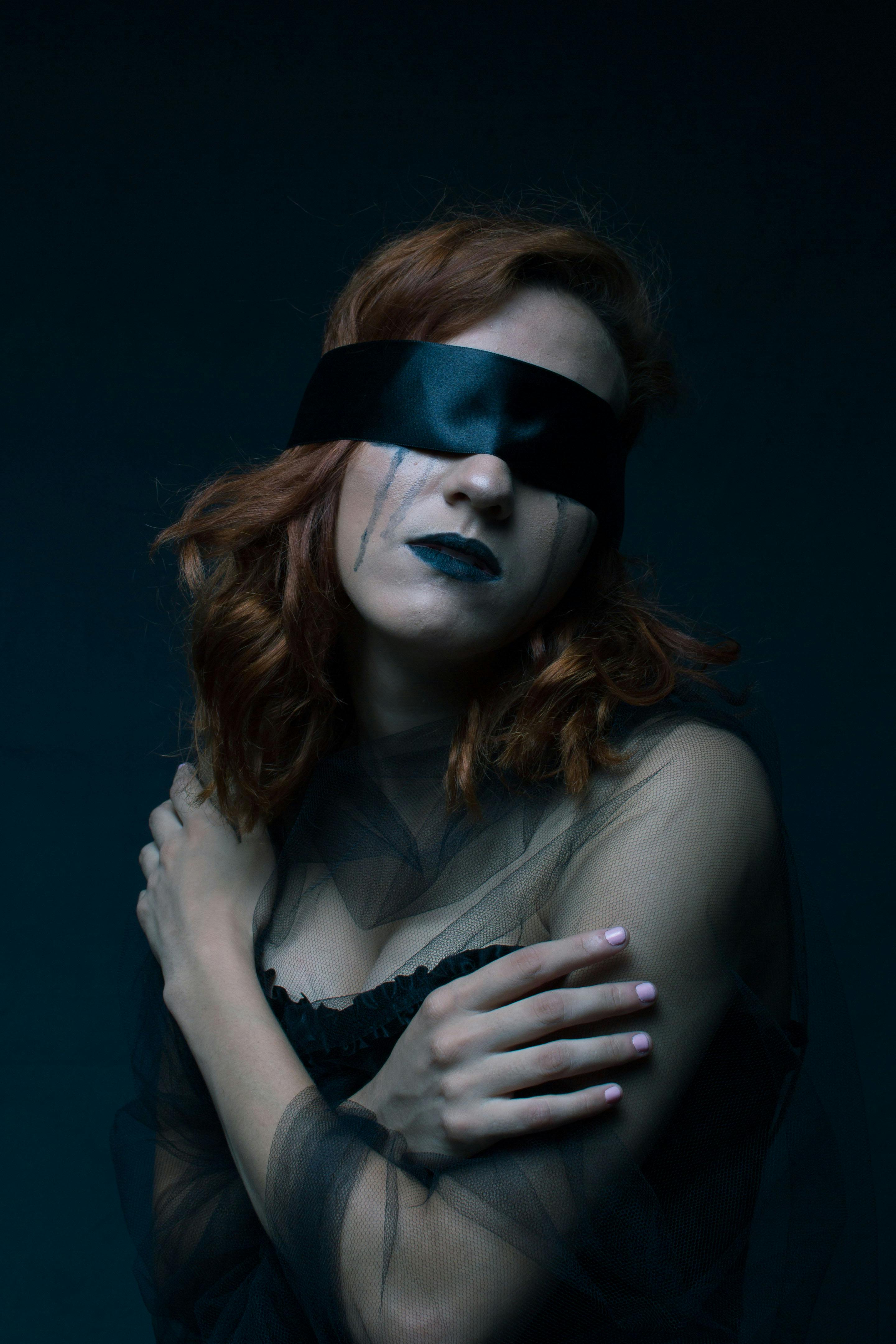 woman wearing black sweetheart neckline dress with black blindfold