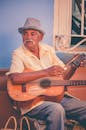 一位年长的吉他手在街头表演，展现了古巴户外音乐场景的活力