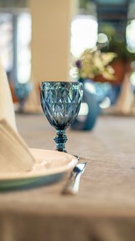 Close-up shot of a classic table setting featuring a blue glass goblet on a draped table.