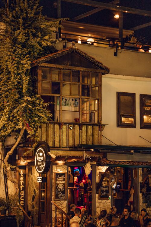 Free Charming urban cafe with outdoor seating and warm lighting, creating a cozy evening atmosphere. Stock Photo