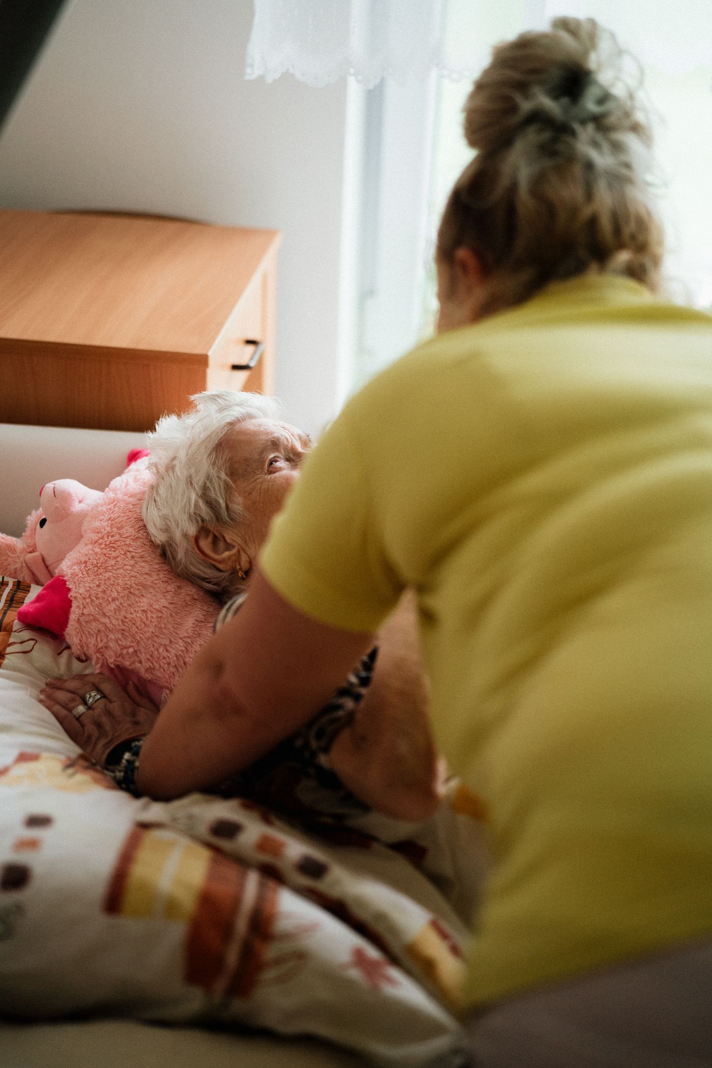 A nurse offering attentive bedside support to an older adult.