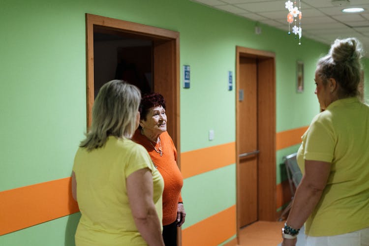 Caregivers Talking With Patient In Hallway