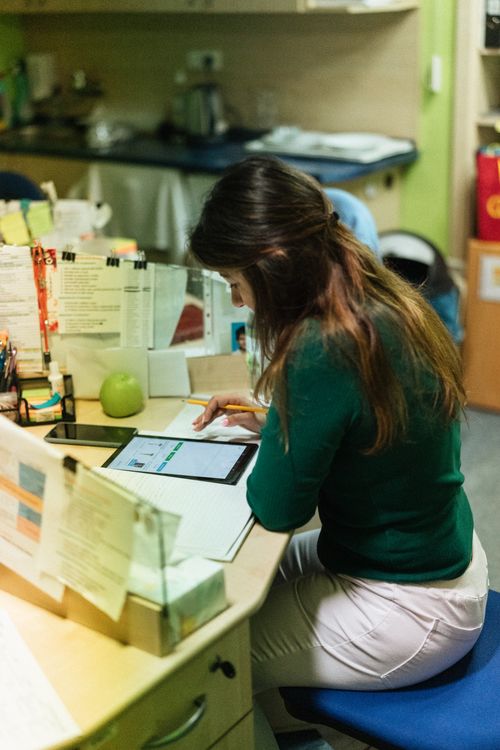 Free A woman sits at a desk using a tablet in a healthcare facility. Stock Photo