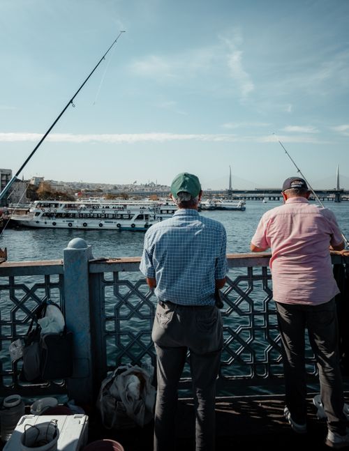 Free Scenic view of fishermen standing on Galata Bridge in Istanbul, Turkey with urban coastal backdrop. Stock Photo