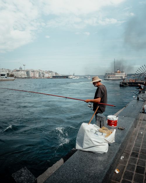 Free A man fishes by the shore in Istanbul, capturing a serene urban moment. Stock Photo