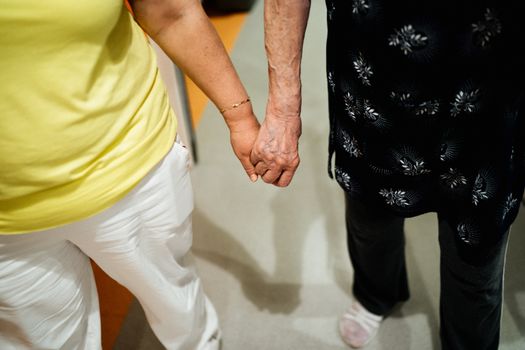 Top view of elderly and adult women holding hands, symbolizing support and connection.
