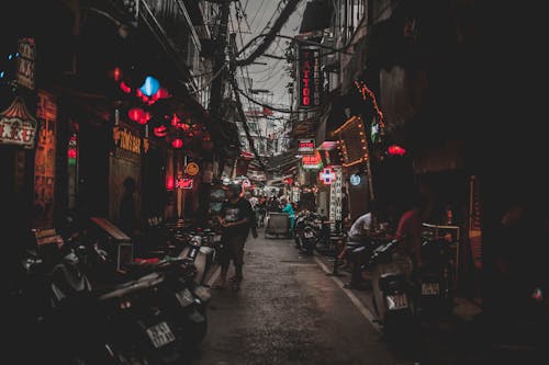 Close-up Photography of People Sitting and Standing Between Buildings