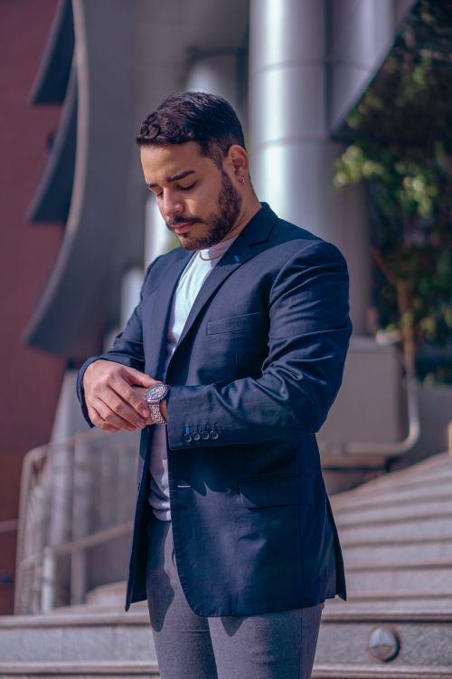 Free Elegantly dressed man checks his watch in a modern outdoor setting. Stock Photo