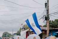 A vibrant celebration in El Salvador featuring a participant proudly waving the national flag.