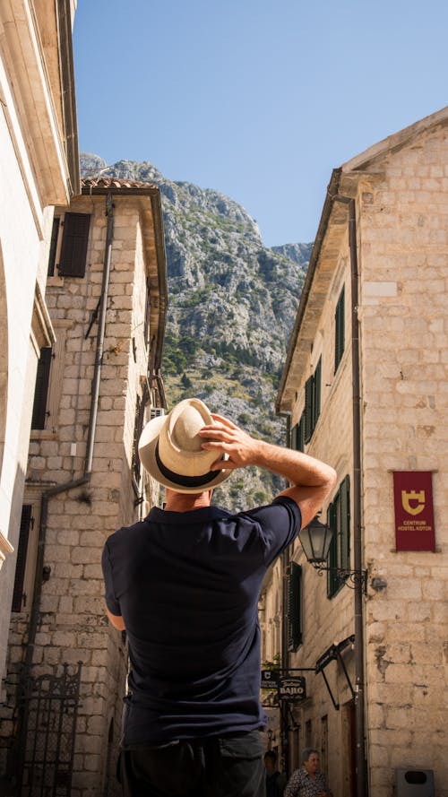 Tourist with Hat Looking at Mountain in Kotor, Montenegro