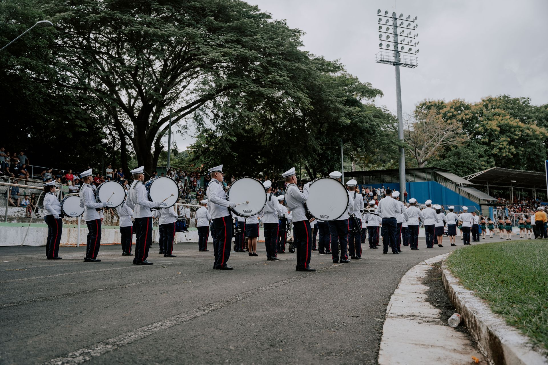 A military parade taking place outdoors with soldiers in uniforms playing drums on a track.