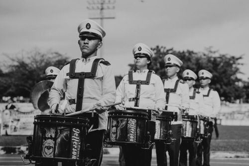 Free Black and white image of a coordinated marching band with drummers in uniform during a parade. Stock Photo