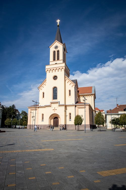 Free A beautiful historic church stands tall in a Serbian town square under a clear blue sky. Stock Photo