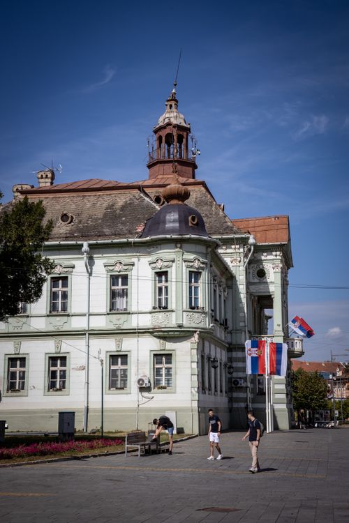 Free Elegant town hall building with Serbian flags in Zrenjanin, capturing a vibrant city scene. Stock Photo