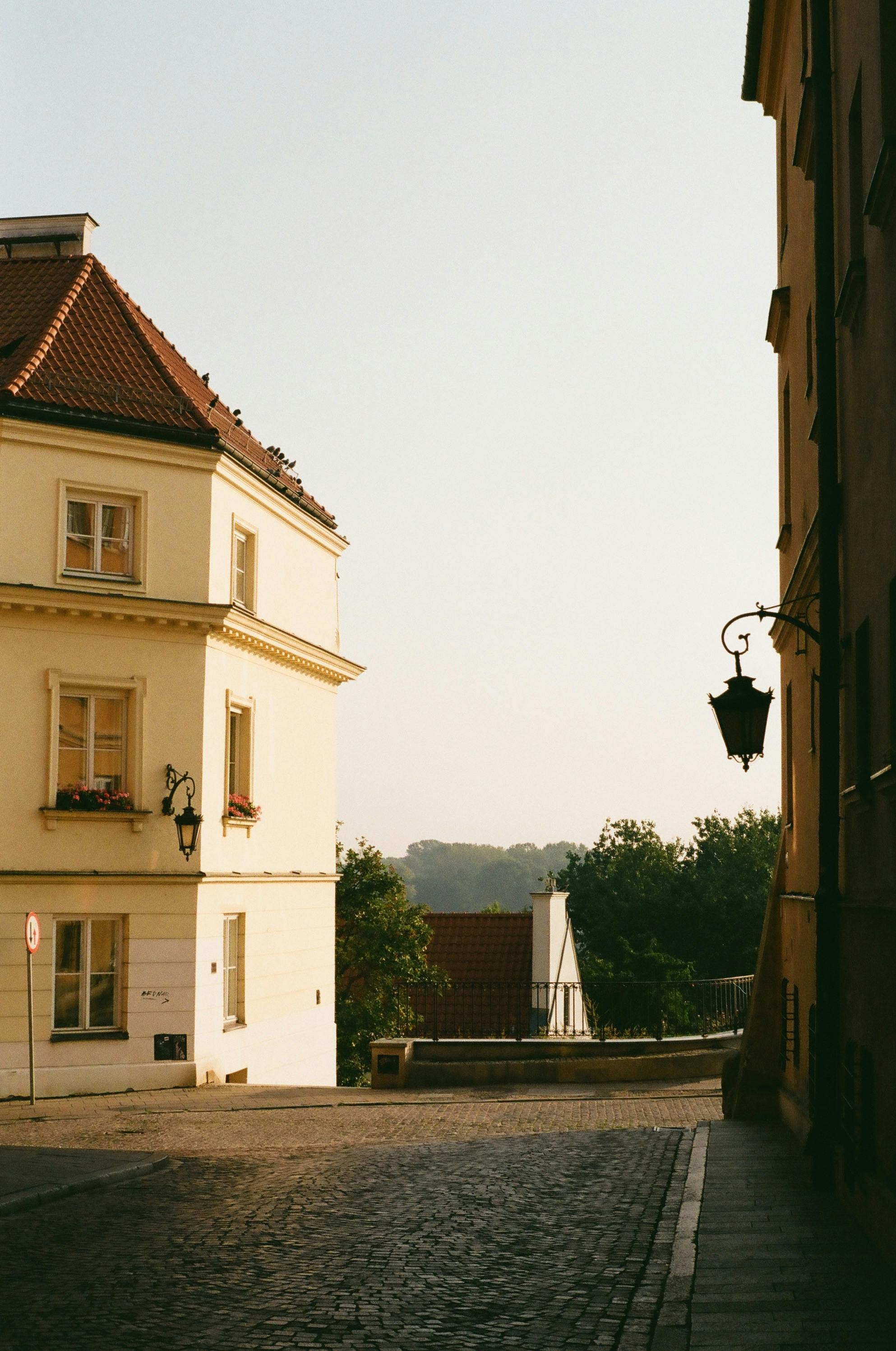 A picturesque cobblestone street in Warsaw, Poland, showcasing historic architecture under a warm sky.