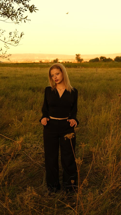 Female Model Wearing a Black Crop Top Standing in a Meadow at Dusk