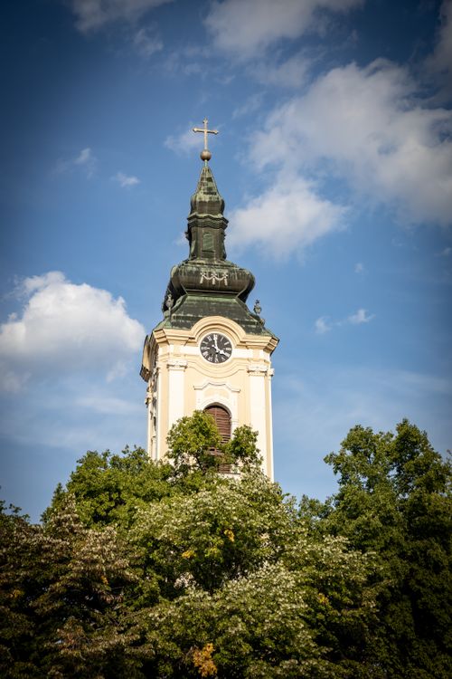 Free Majestic view of Saint Nicholas Church bell tower surrounded by lush greenery, under a clear blue sky. Stock Photo